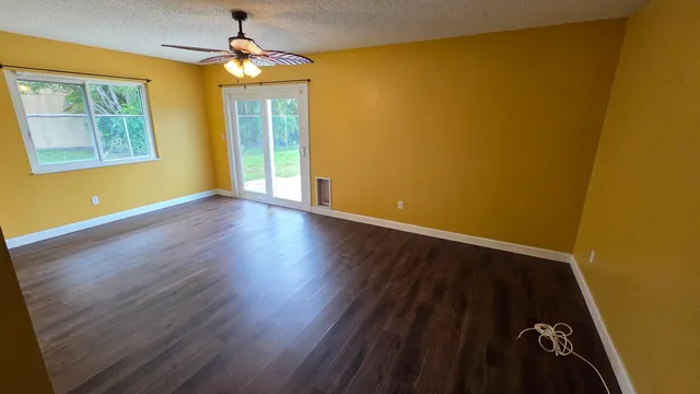 a view of an empty room with wooden floor and a window