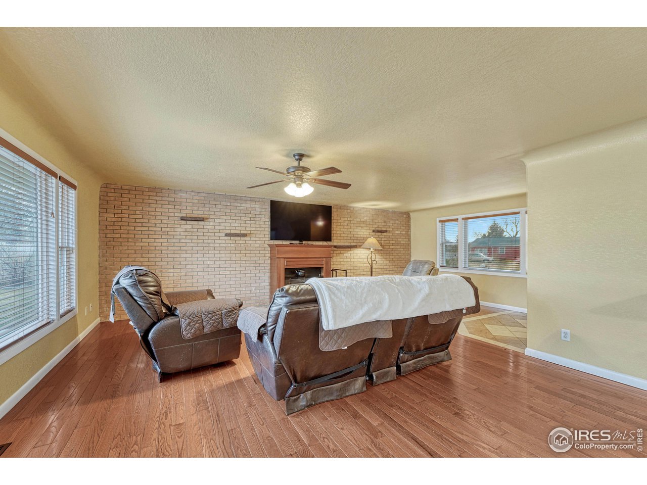 2518 Highland Road Greeley, CO 80634 - Photo 8 of 40 Living room with wood floors, wood burning insert in fireplace and brick interior wall with built in shelves.