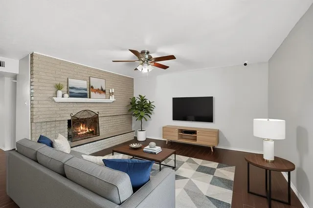 a view of a livingroom with a fireplace a ceiling fan and wooden floor
