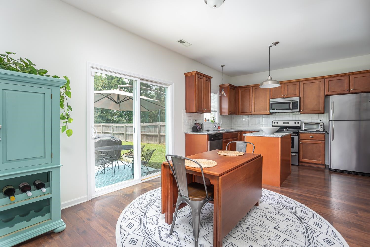 322 Forest Lane Wendell, NC 27591 - Photo 20 of 37 a kitchen with stainless steel appliances granite countertop a stove a sink a microwave a refrigerator a dining table and chairs with wooden floor