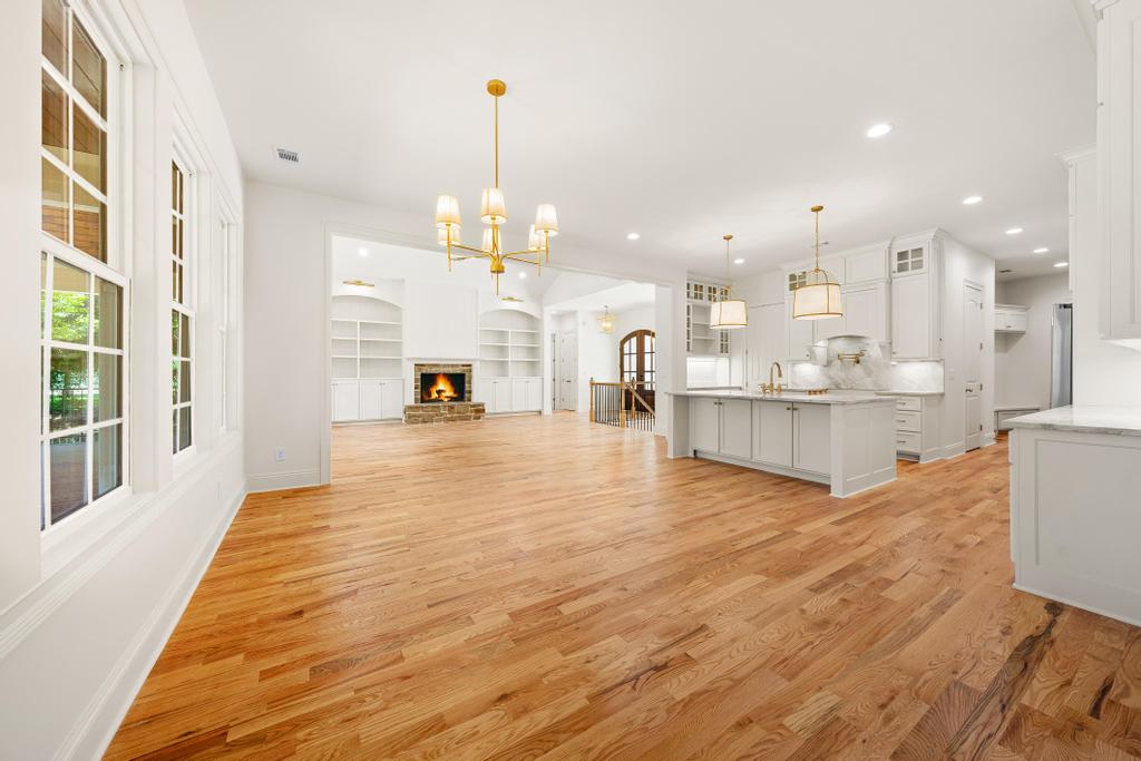 707 Vickery Street Extension Hartwell, GA 30643 - Photo 14 of 50 Golden hardwood floors extend through this open-concept home, featuring a prominent fireplace and a well-appointed kitchen.