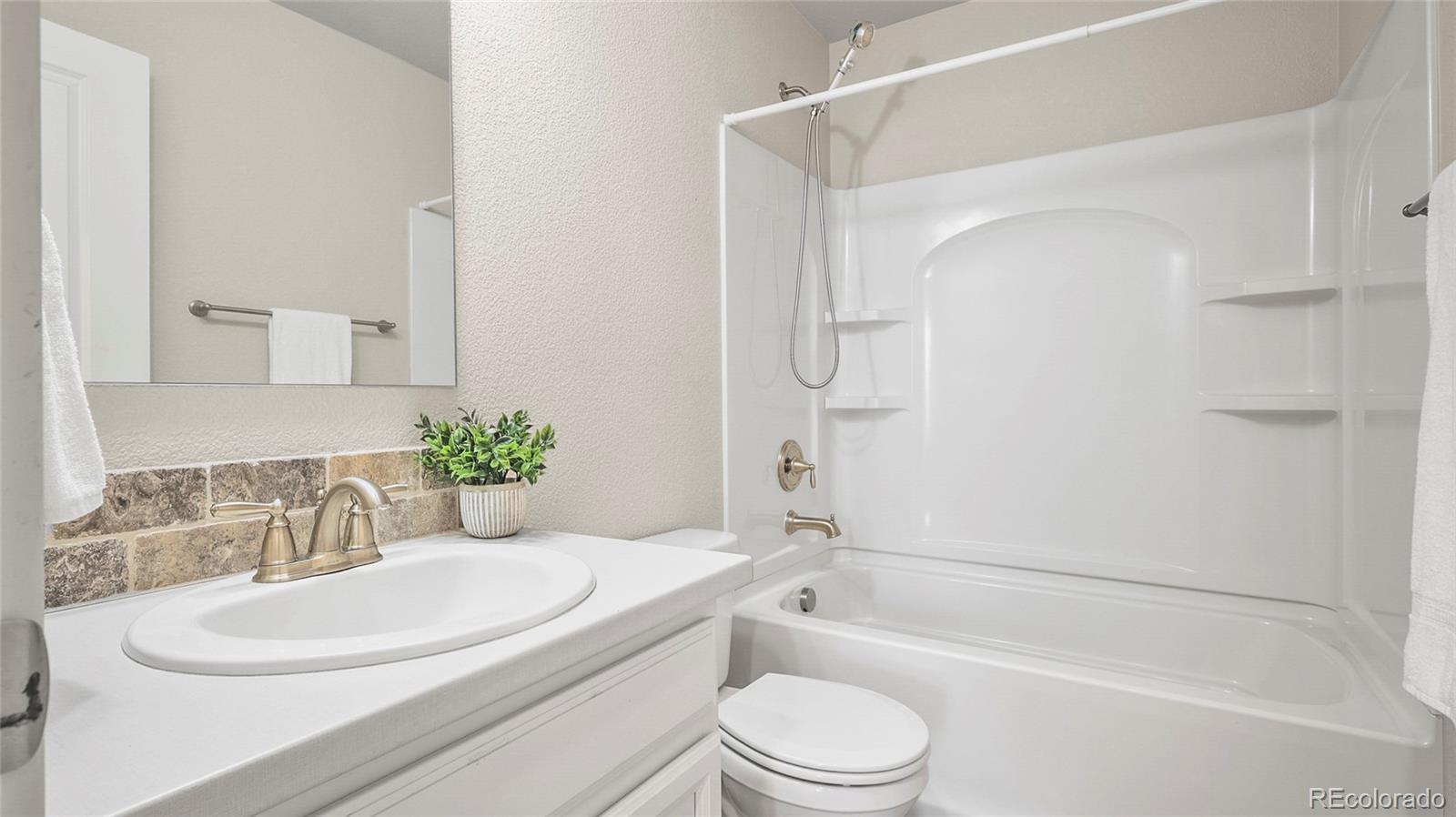 1106 Johnson Street Wiggins, CO 80654 - Photo 13 of 22 a bathroom with a granite countertop sink toilet a mirror and shower