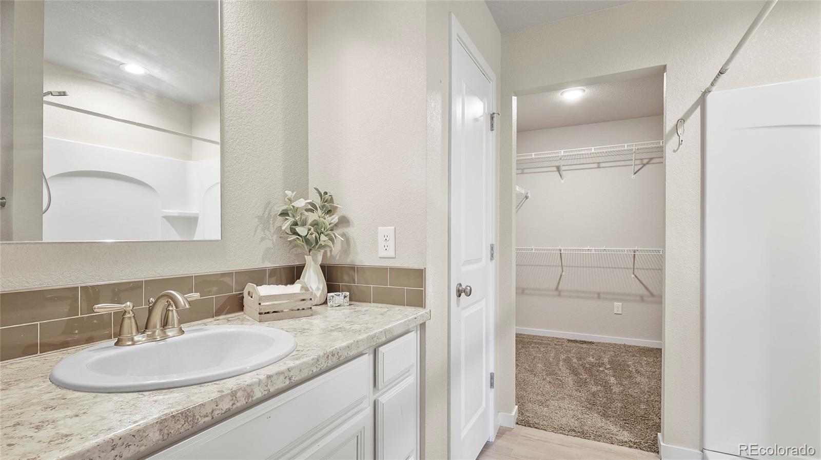1106 Johnson Street Wiggins, CO 80654 - Photo 8 of 22 a bathroom with a granite countertop sink a mirror and a shower