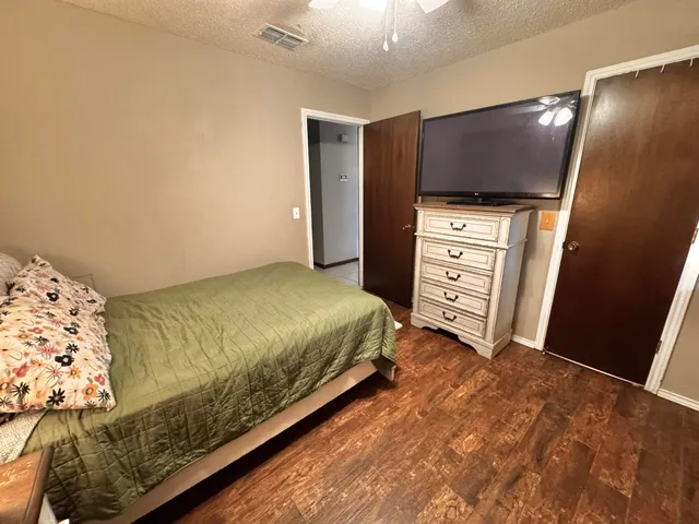 a bedroom with a bed and a flat tv screen on the dresser