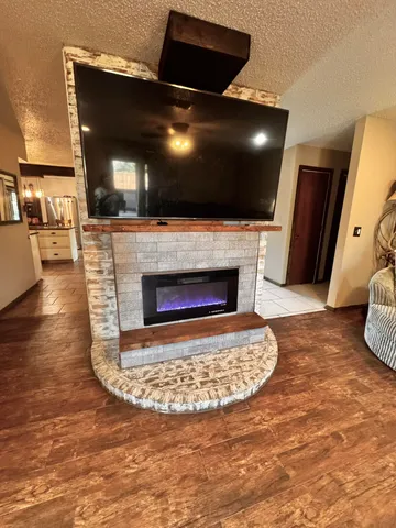 a living room with a fireplace a flat screen tv and kitchen view