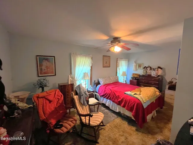 a bed room with a bed mirror and a flat tv screen on dresser