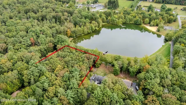 an aerial view of a residential houses with outdoor space and trees all around