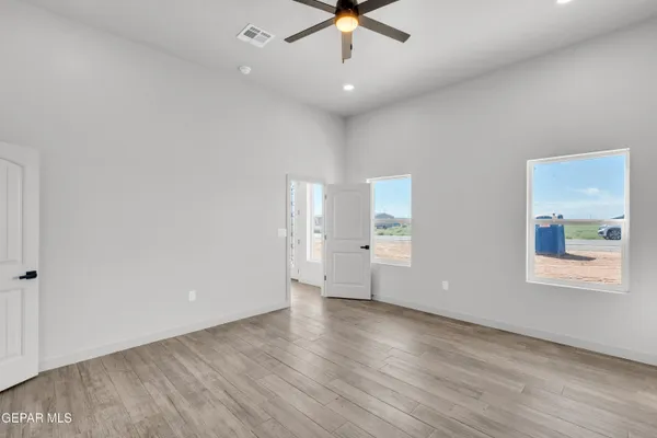 an empty room with wooden floor fan and windows