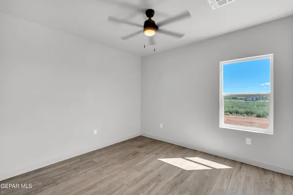 an empty room with a window and a ceiling fan