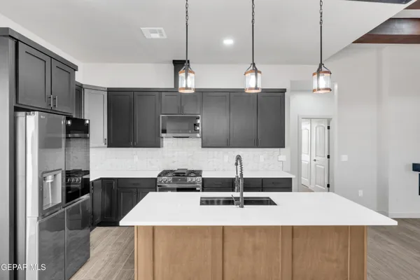 a large kitchen with kitchen island a sink stainless steel appliances and refrigerator