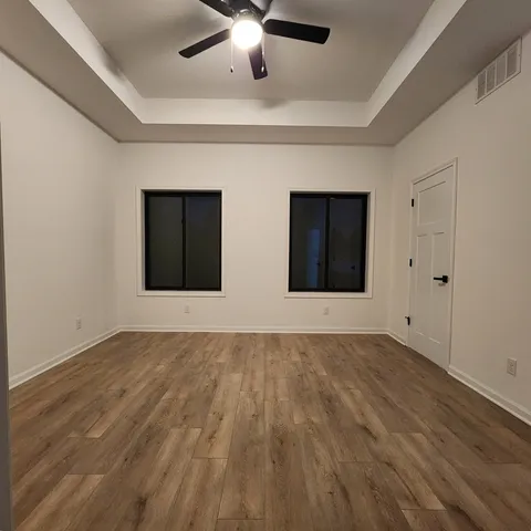 a view of an empty room with window and wooden floor