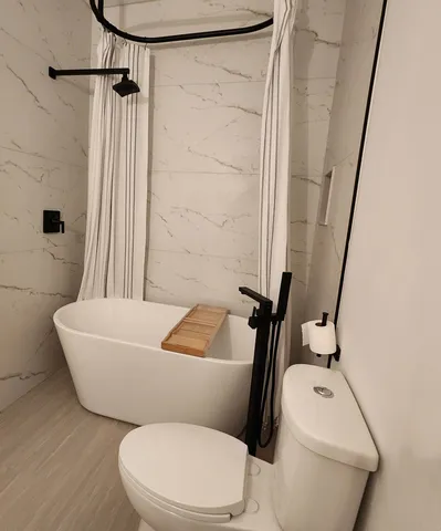 a white toilet sitting next to a bath tub