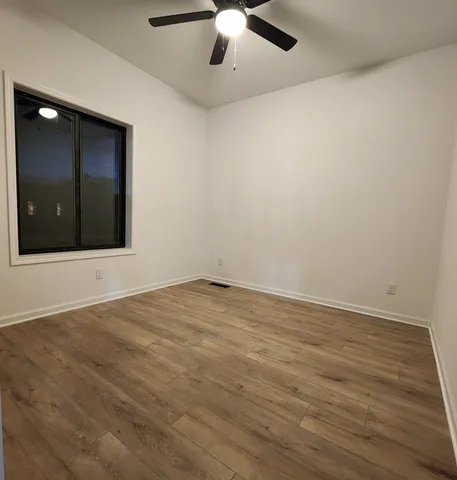 an empty room with wooden floor and fan