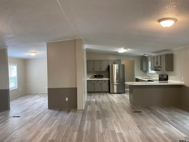 a kitchen with stainless steel appliances kitchen island granite countertop a stove a sink and a refrigerator