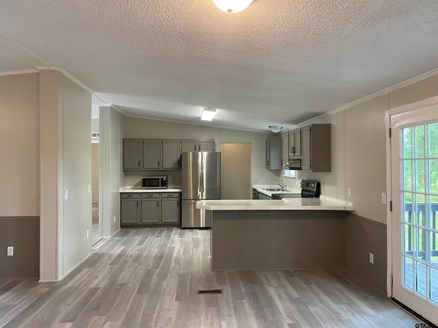 a kitchen with stainless steel appliances granite countertop a sink cabinets and wooden floor
