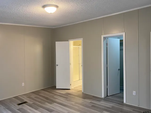 a view of an empty room with wooden floor and closet