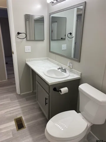 a bathroom with a toilet a sink a mirror and vanity