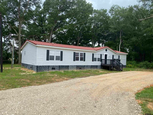 a front view of a house with a yard deck and trees