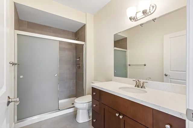 a bathroom with a sink a toilet a shower and a large mirror