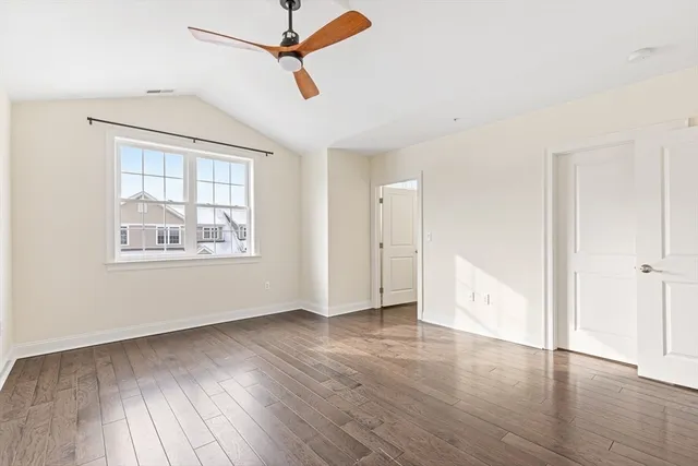 an empty room with wooden floor chandelier fan and windows