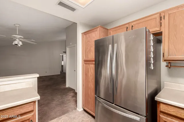a view of a refrigerator in kitchen and an empty room