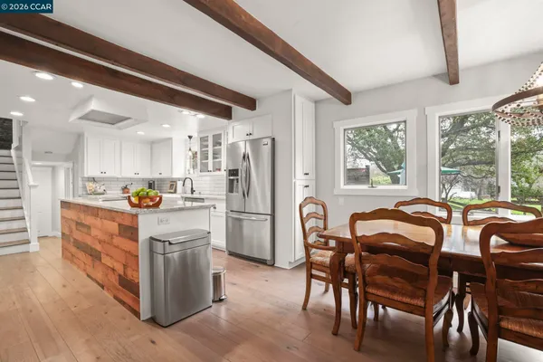 a kitchen with stainless steel appliances granite countertop a table chairs and a refrigerator