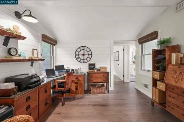 a large kitchen with stainless steel appliances a stove oven a refrigerator a dining table and chairs with wooden floor