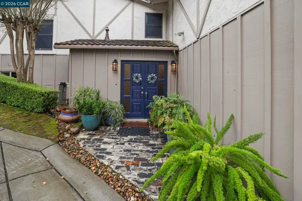 a view of a house with potted plants and a bench