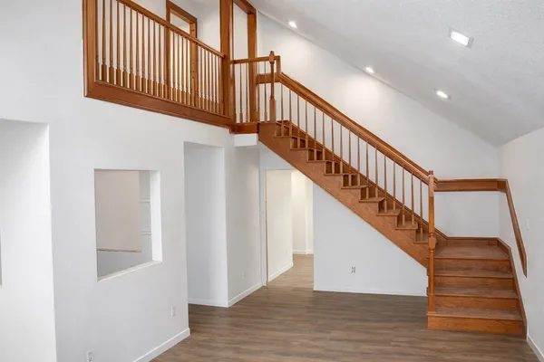 a view of staircase with lots of frames on wall and wooden floor