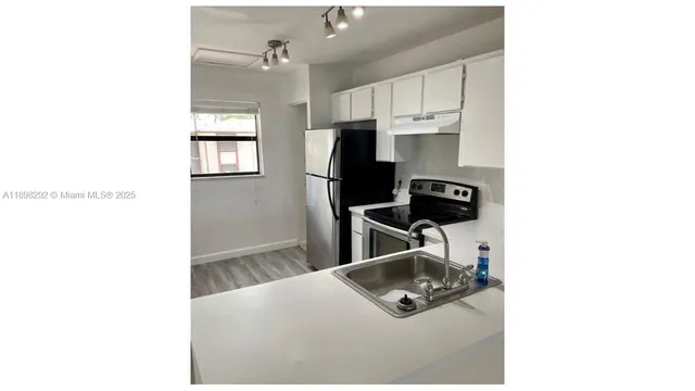 a living room with stainless steel appliances kitchen island granite countertop a sink refrigerator and microwave