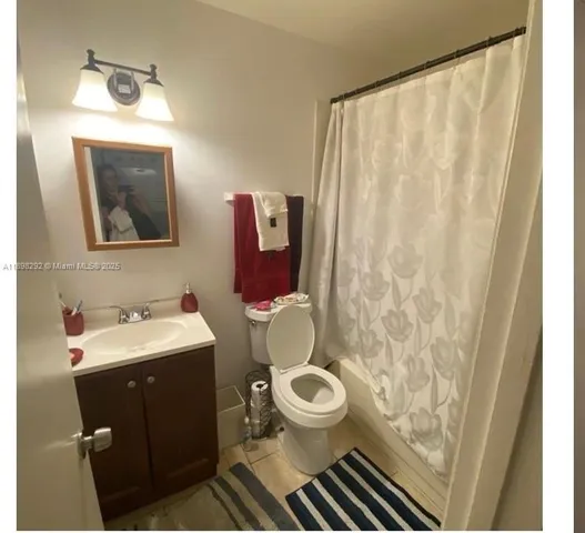 a bathroom with a sink a toilet a mirror and shower curtain
