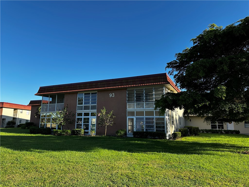 93 Spring Lake Drive, Unit 202 Vero Beach, FL 32962 - Photo 1 of 18 a front view of a house with a garden