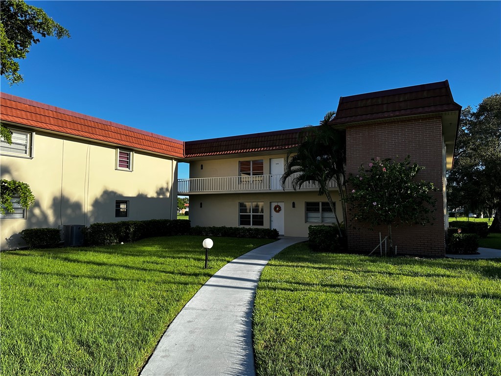 93 Spring Lake Drive, Unit 202 Vero Beach, FL 32962 - Photo 2 of 18 a front view of house with yard and green space