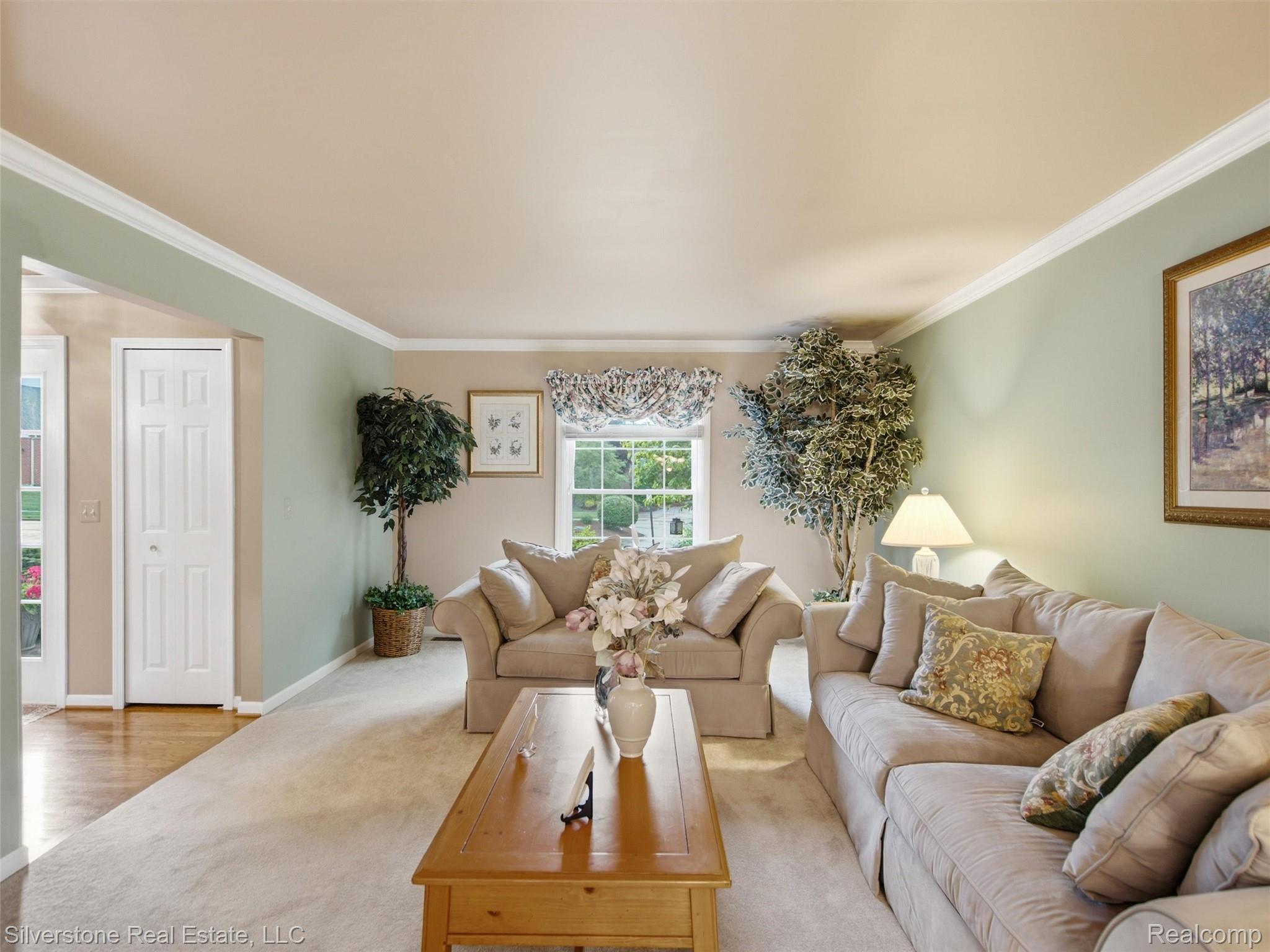 6577 Edith Court Troy, MI 48085 - Photo 17 of 61 Carpeted living area featuring a window with a valance, crown molding, and an arched entry to a wood-finish flooring area