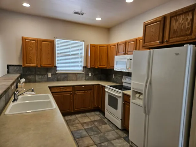 a kitchen with stainless steel appliances granite countertop a refrigerator sink and stove