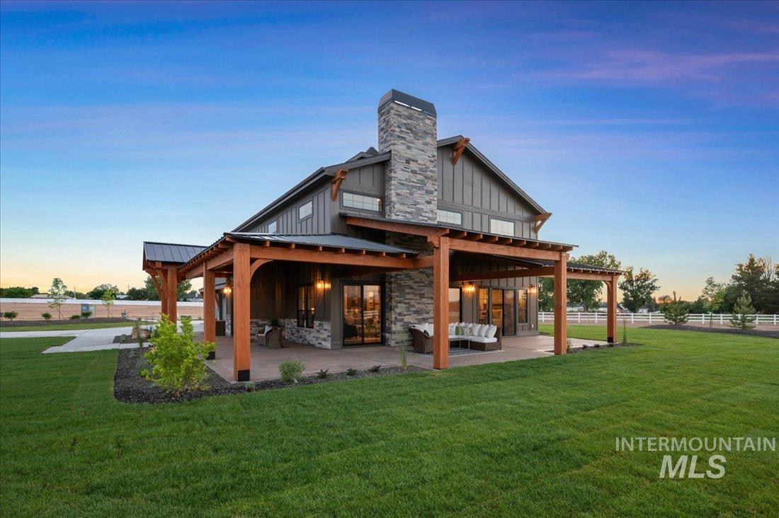 8860 Kemp Middleton, ID 83644 - Photo 1 of 50 Back of house featuring board and batten siding, a patio area, a chimney, and a lawn