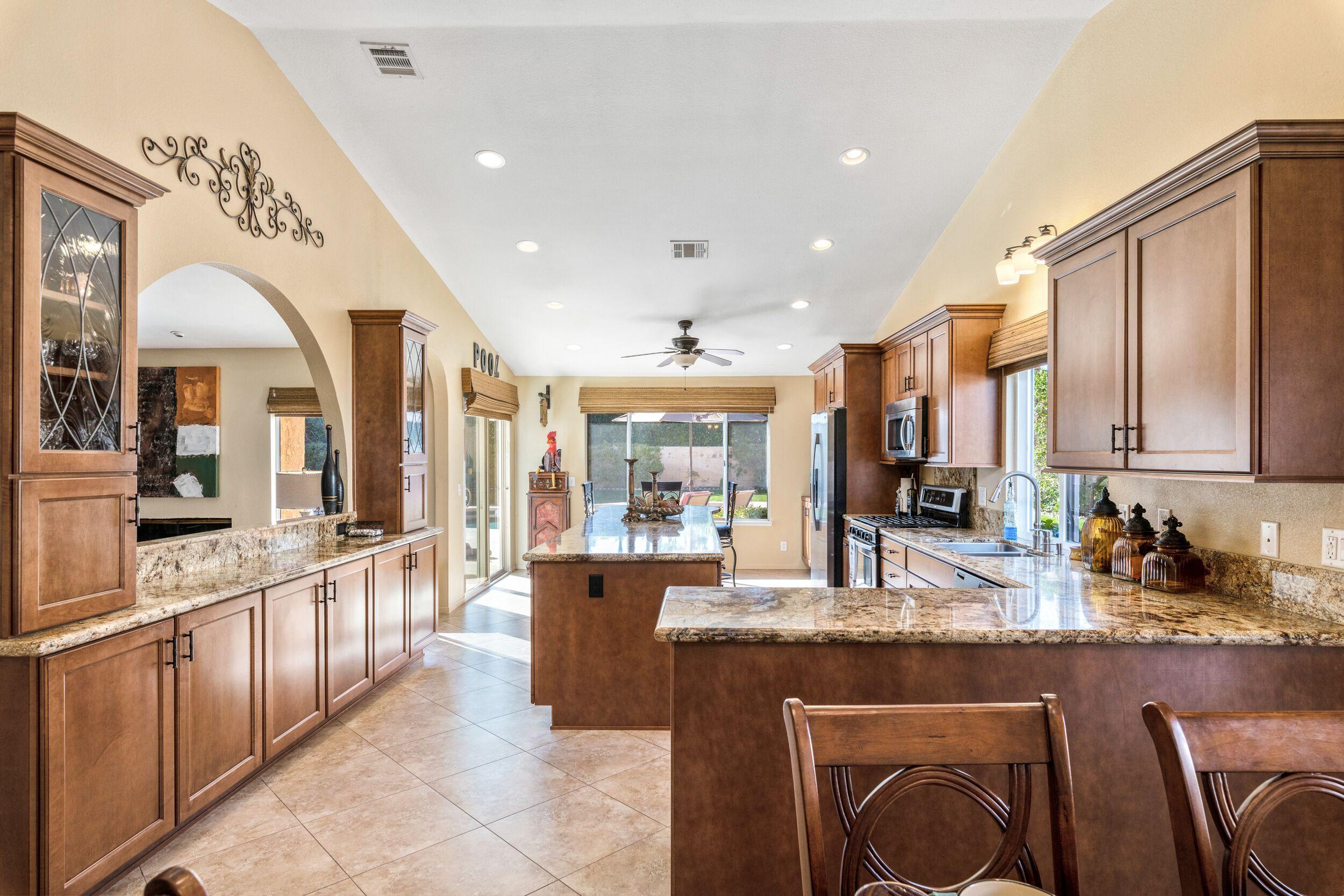 39795 Regency Way Palm Desert, CA 92211 - Photo 16 of 39 a large kitchen with kitchen island granite countertop a large counter top space a sink stainless steel appliances and cabinets