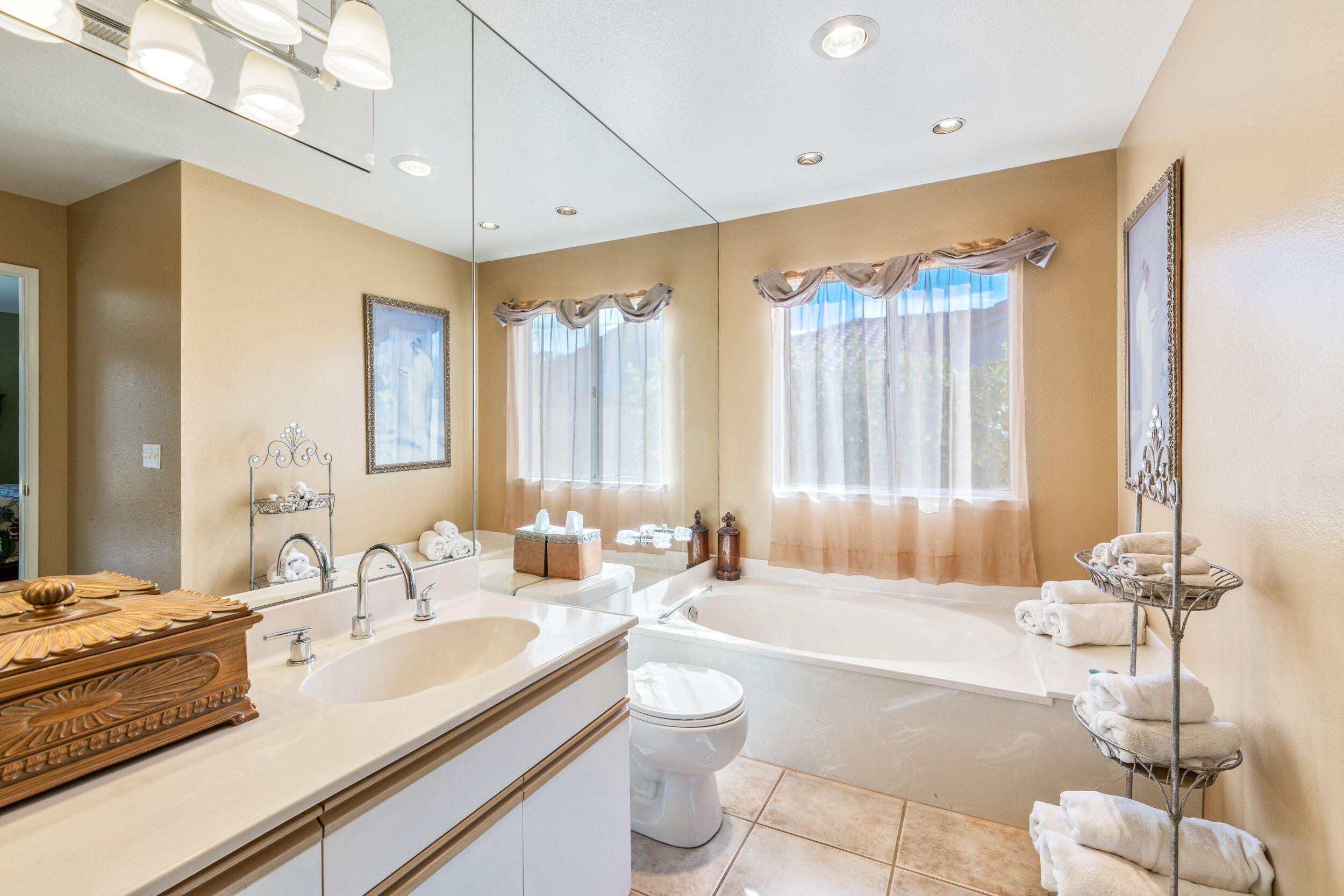 39795 Regency Way Palm Desert, CA 92211 - Photo 27 of 39 a spacious bathroom with a double vanity sink a large mirror and a bathtub