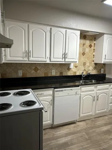 a kitchen with granite countertop white cabinets and black appliances