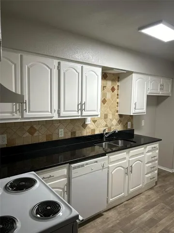 a kitchen with granite countertop a sink a stove and cabinets