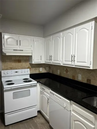 a kitchen with granite countertop white cabinets and white appliances
