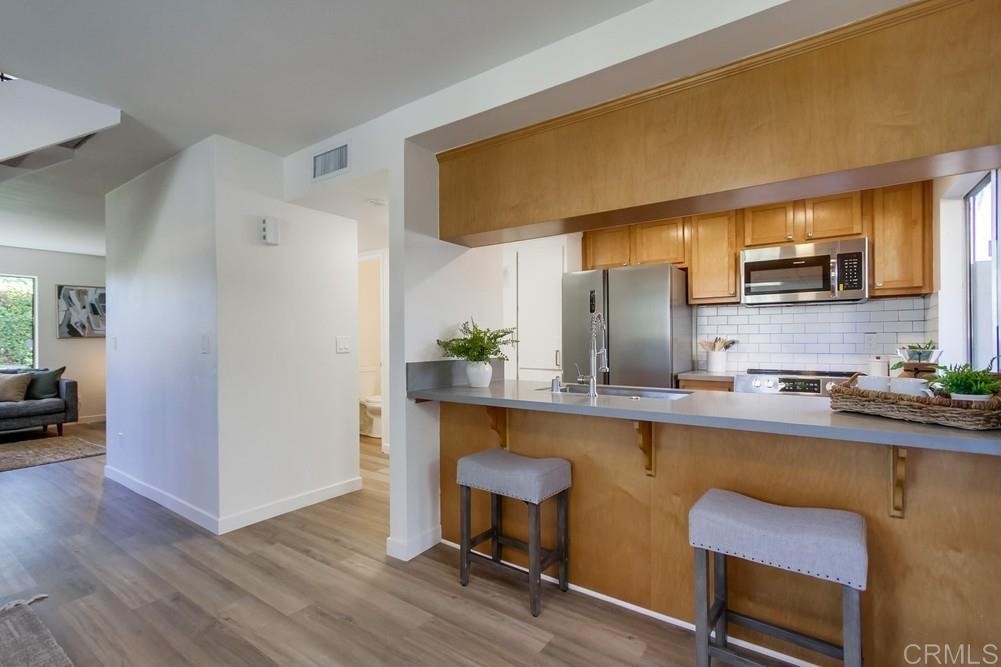 11941 Royal Road, Unit A El Cajon, CA 92021 - Photo 4 of 28 a kitchen with stainless steel appliances a sink cabinets and wooden floor