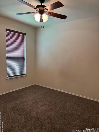 an empty room with a window and a fan
