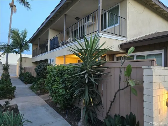 a view of a house with a small yard and floor to ceiling window and potted plants