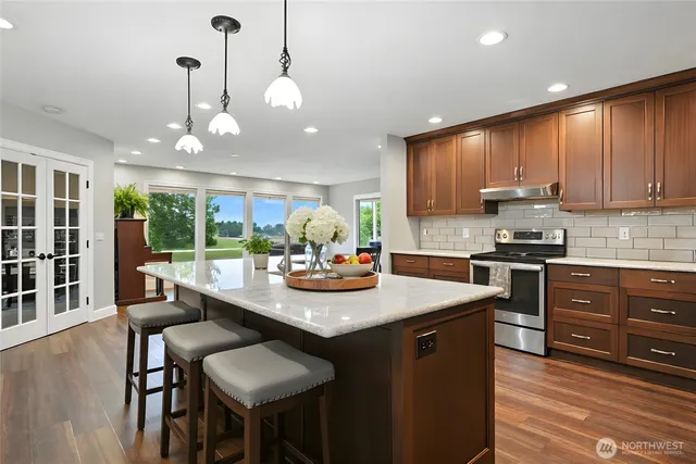 a kitchen with a stove a sink a kitchen island with chairs and wooden floor