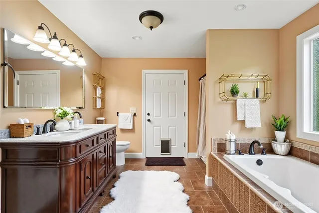 a spacious bathroom with a tub a double vanity sink a window and a mirror