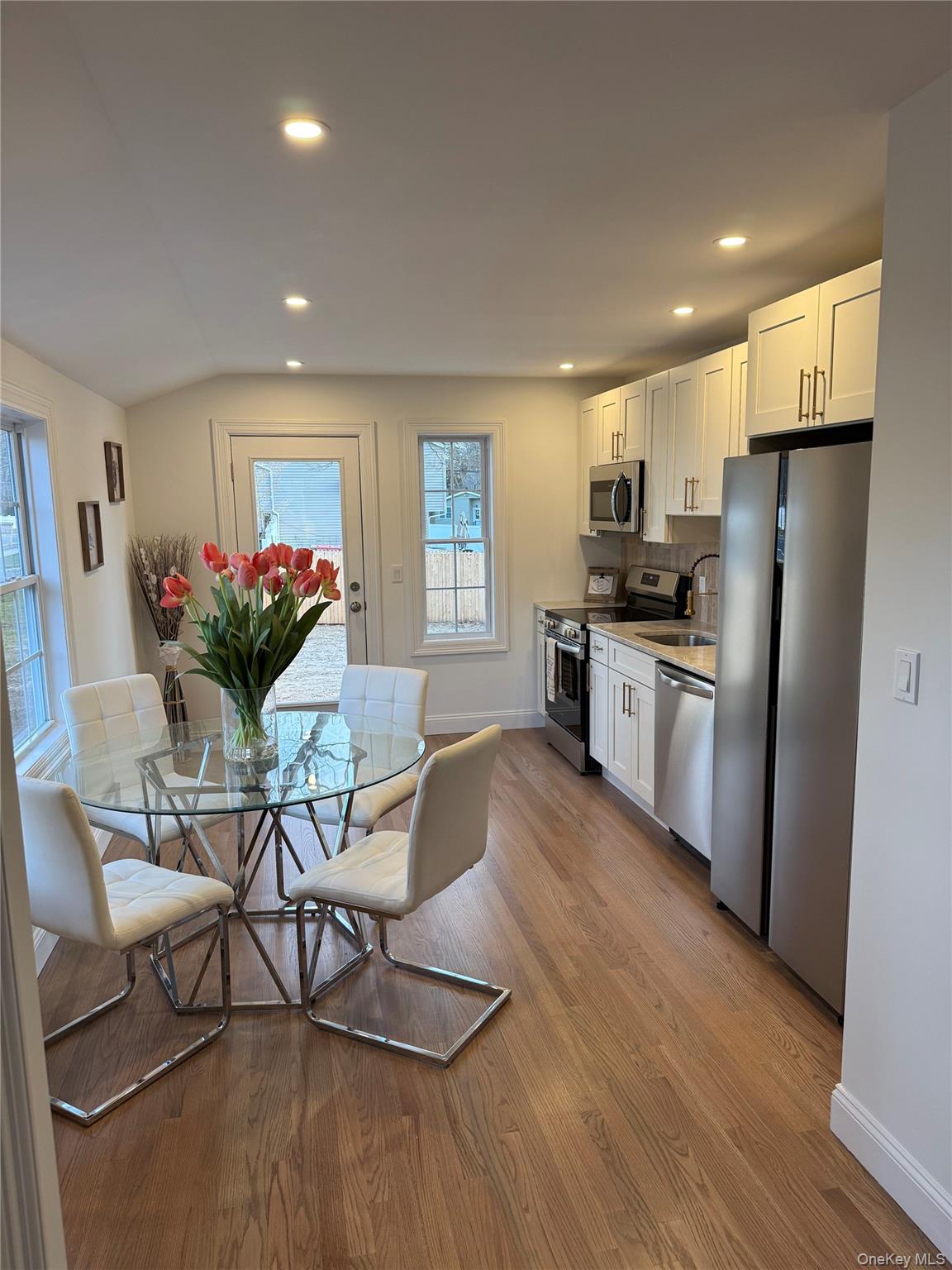 661 College Road Farmingville, NY 11738 - Photo 3 of 19 Kitchen featuring stainless steel appliances, white cabinetry, dark wood-style flooring, recessed lighting, and light countertops