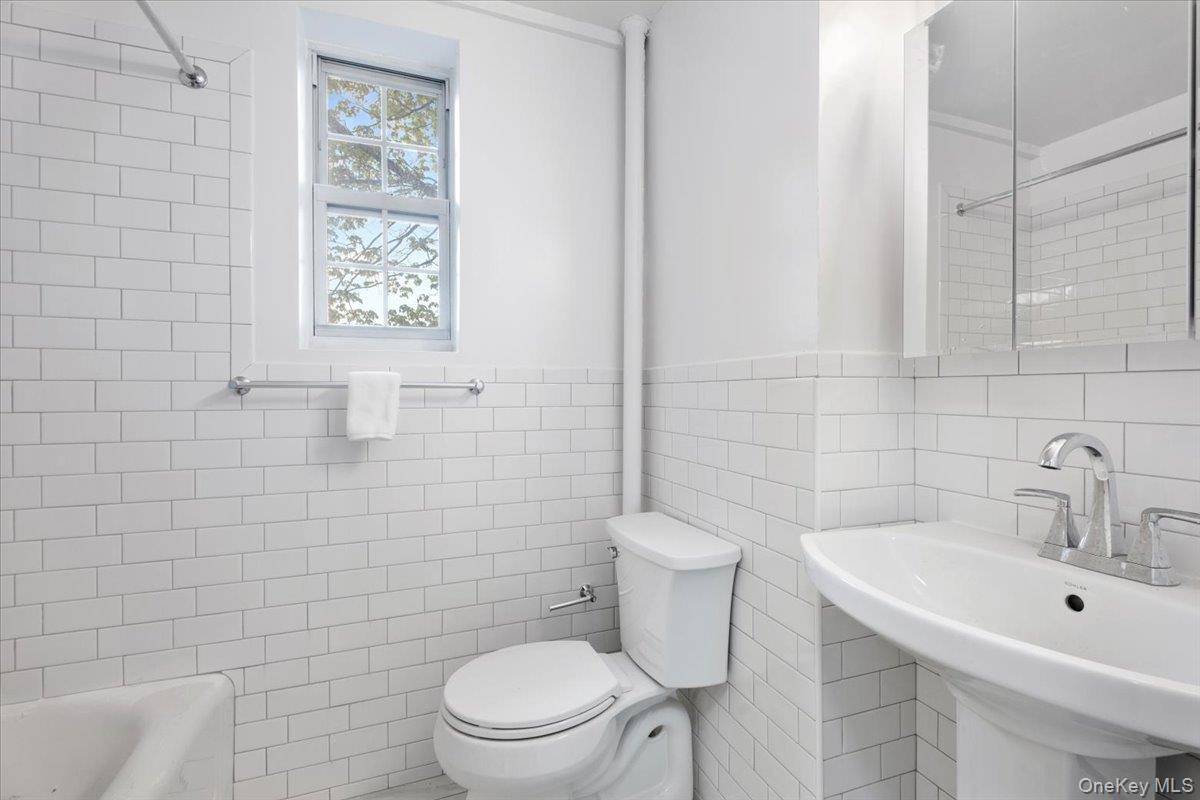 45 Popham Road, Unit 1E Scarsdale, NY 10583 - Photo 12 of 24 a bathroom with a toilet a sink a mirror and shower