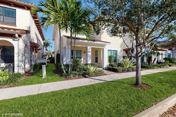a front view of a house with a garden and tree