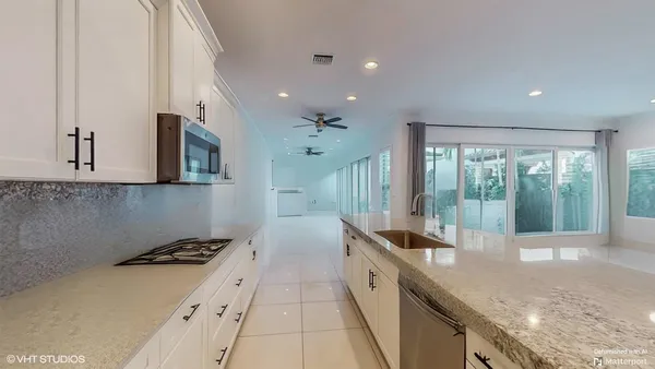 a kitchen with granite countertop a sink and white cabinets